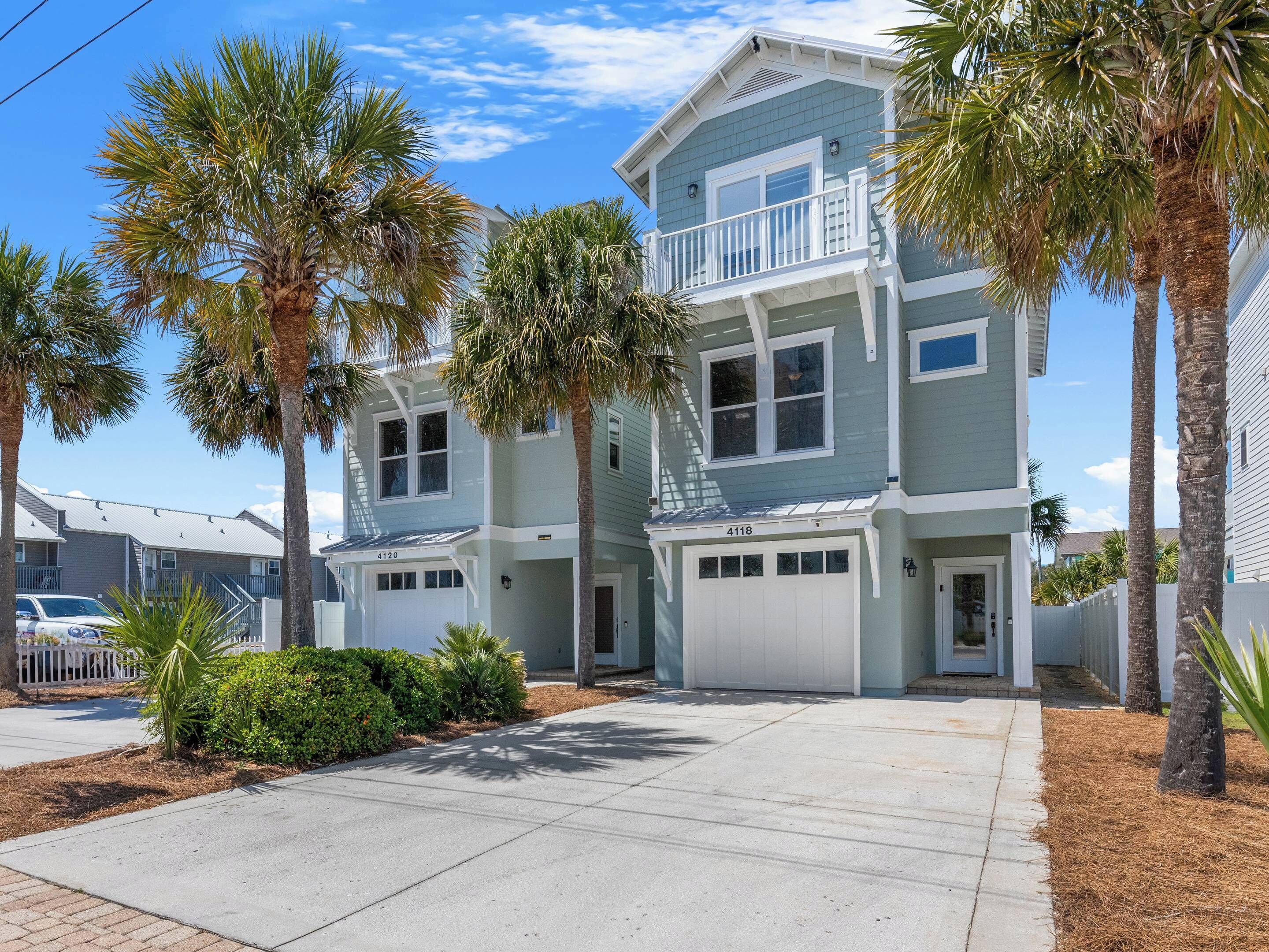 A two-story beachfront condominium with a balcony, a garage, and a well-maintained lawn.