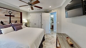 A bedroom with a bed, a ceiling fan, a TV mounted on the wall, and a wooden headboard. - Paradise Isle #15A by Southern Vacation Rentals (Gulf Shores)