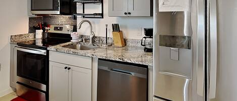 A modern kitchen with stainless steel appliances, a built-in oven, microwave, and dishwasher, and a red rug on the floor.