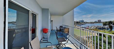 A balcony with outdoor seating, a view of the marina, and a cityscape in the background.