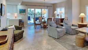 A spacious living area with a dining table, sofas, and a kitchen in the background. - South Harbour #2F by Southern Vacation Rentals (Pensacola Beach)