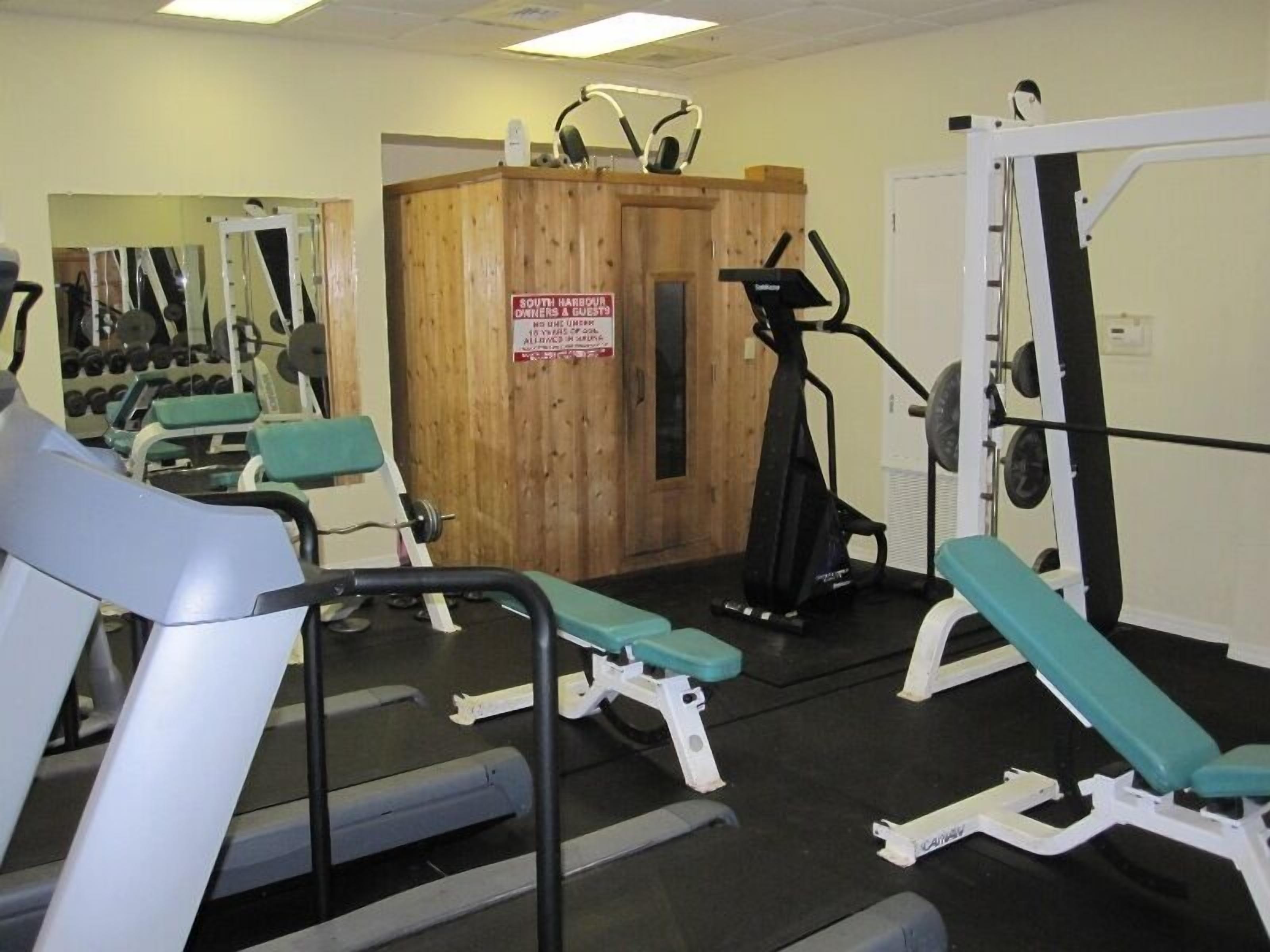 A gym with exercise equipment, including a treadmill, weight machines, and a bench.
