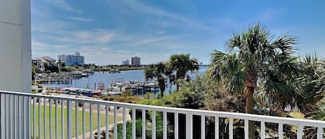 A balcony with a view of a marina, palm trees, and distant buildings.