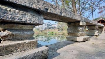 A stone bridge with a pond underneath, leading to a building with a reflection.