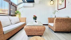 Un salon moderne avec des meubles en osier, une table basse en verre et un ventilateur de plafond.