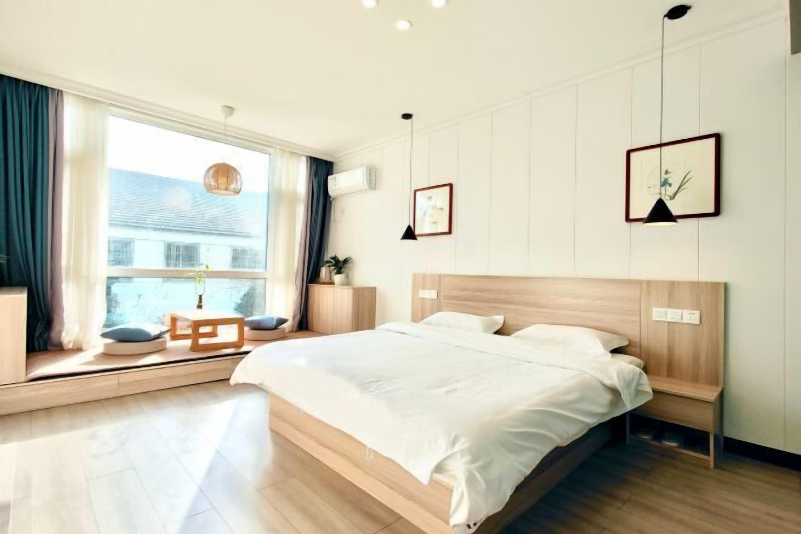 Um quarto moderno com uma cama grande, uma mesa de cabeceira, uma janela com cortinas e vista para o exterior.