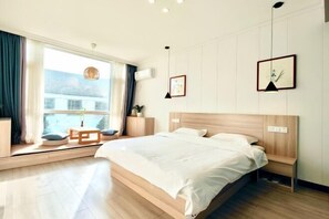 A modern bedroom with a large bed, a bedside table, a window with curtains, and a view of the outside. - Changzhou Lihua Xiaoyuan Inn (Changzhou)