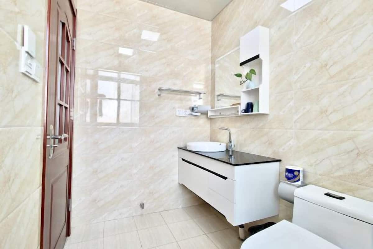 Une salle de bain moderne avec un sol en marbre, un lavabo blanc, un miroir et des toilettes.