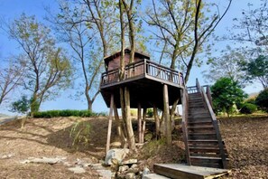 A wooden treehouse with a staircase leading up to a platform.