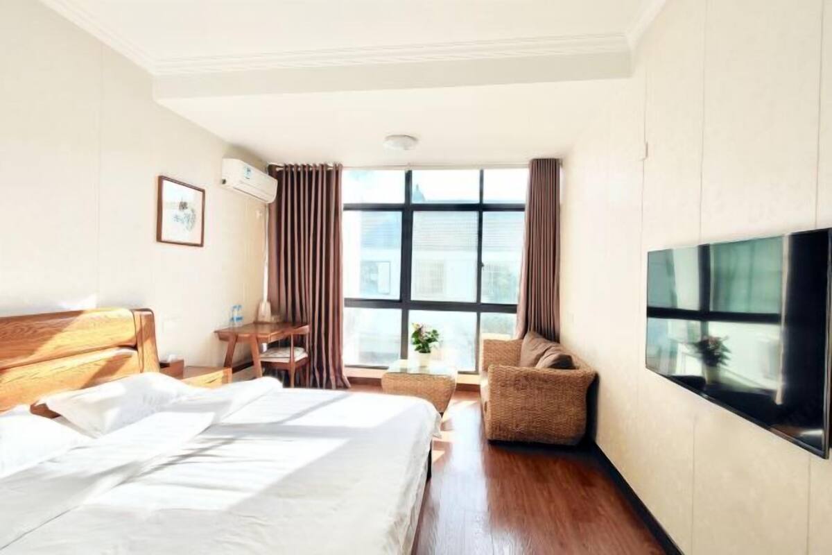 Une chambre d’hôtel avec un lit, un bureau, une chaise, une télévision et une fenêtre.