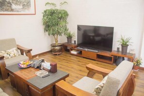 Ein Wohnzimmer mit Fernseher, Holzmöbeln und Topfpflanzen.