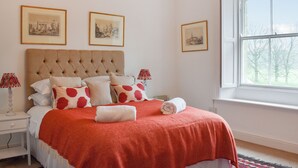 Un dormitorio con una cama grande, una ventana con vistas a árboles y tres cuadros en la pared.