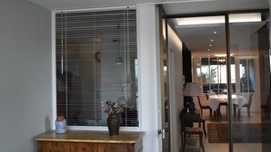 A modern interior with a wooden cabinet, a dining area with a table and chairs, and a glass door leading to another room. - Terrasses sur la mer (Sète)
