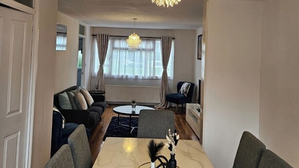 A modern living room with a marble dining table, grey upholstered chairs, a black sofa, and a chandelier. - City Classic- Remarkable 3-bed House in Birmingham (Birmingham)