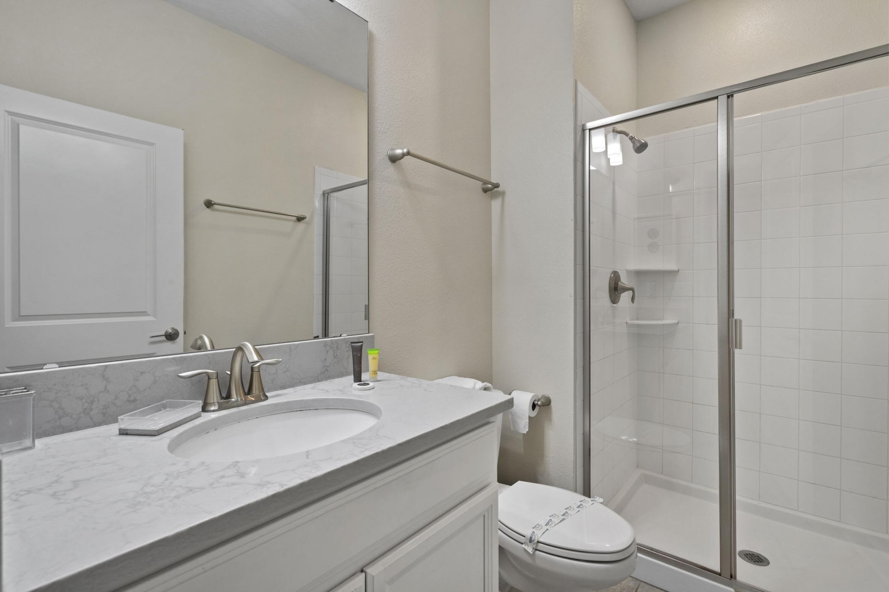 A bathroom with a marble sink, a toilet, and a glass-enclosed shower.