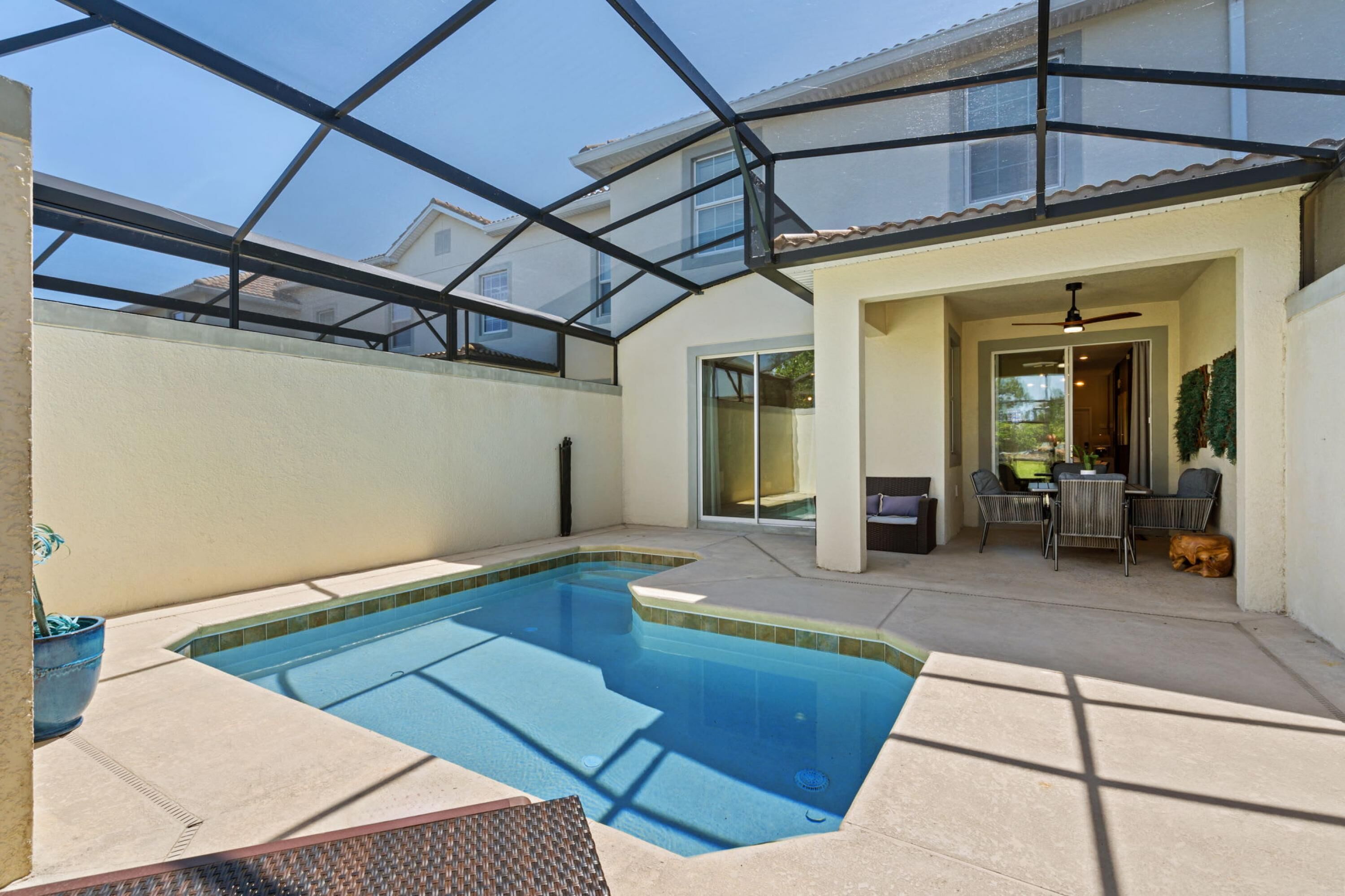 A swimming pool with a glass ceiling, a patio area with a table and chairs, and a dog lying nearby.