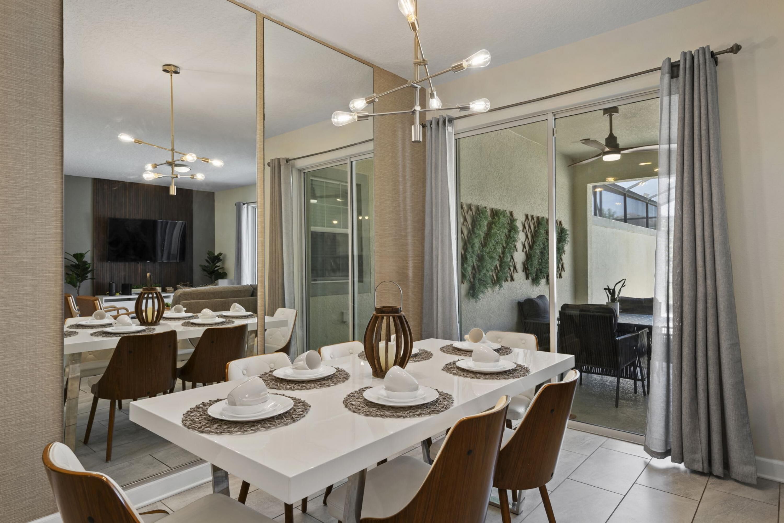 A modern dining area with a white table set for six, surrounded by wooden chairs.