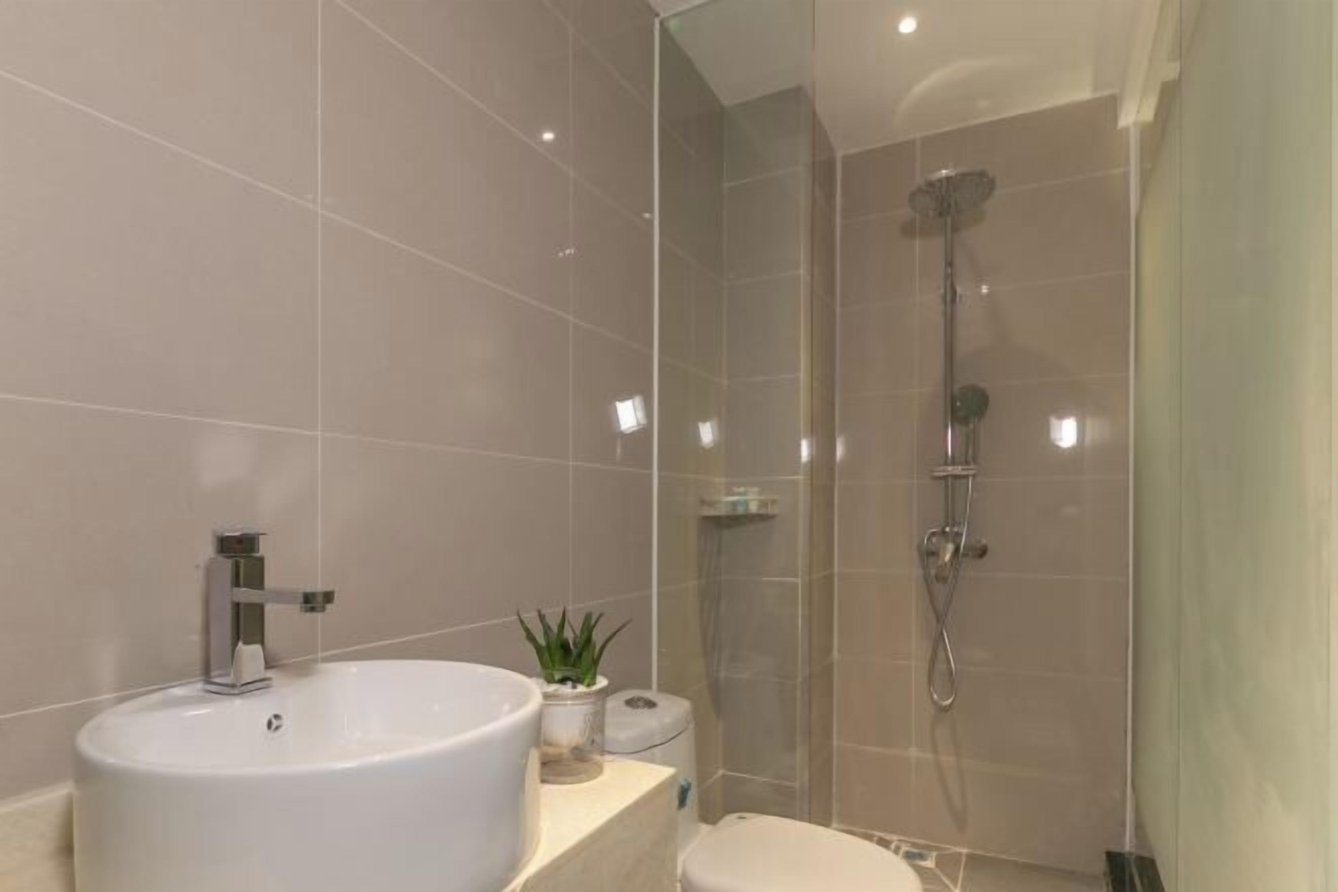 Une salle de bain moderne avec un grand lavabo blanc, des toilettes et une douche séparée par une paroi de verre.