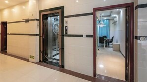 A hotel corridor with an elevator, a reception area, and a dining space.