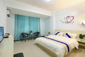 A hotel room with a bed, a desk, a chair, a small table, and a curtain. - Sanya Haitang Bay Rujia Hotel (Sanya)