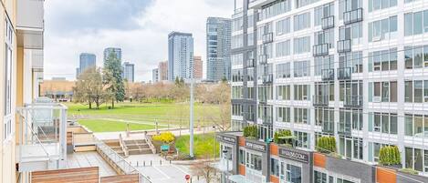 Un bâtiment moderne doté d’une façade en verre, d’un espace de stationnement et offrant une vue sur un parc et le paysage urbain.