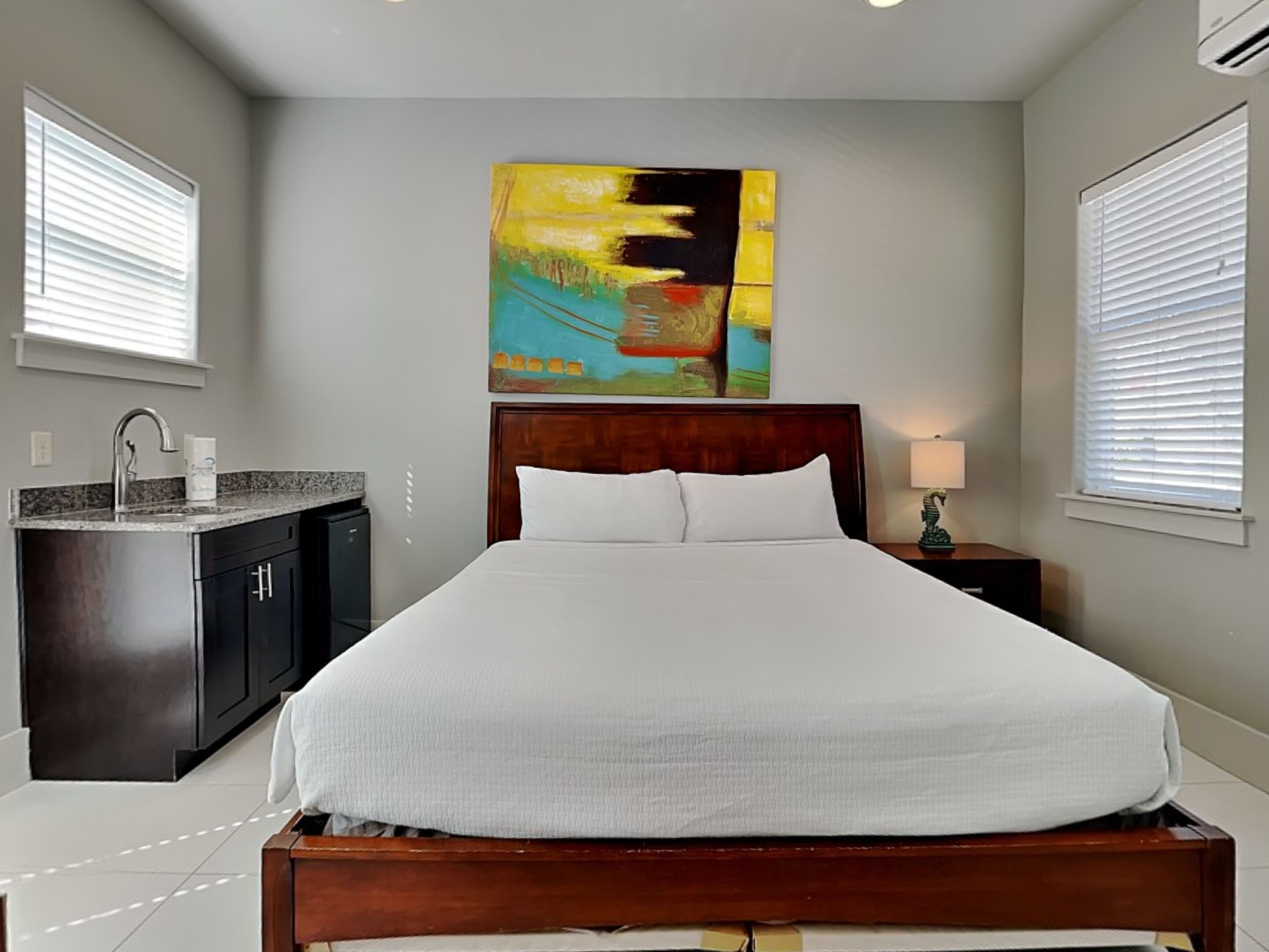 A bedroom with a bed, a nightstand, a sink, and a cabinet.