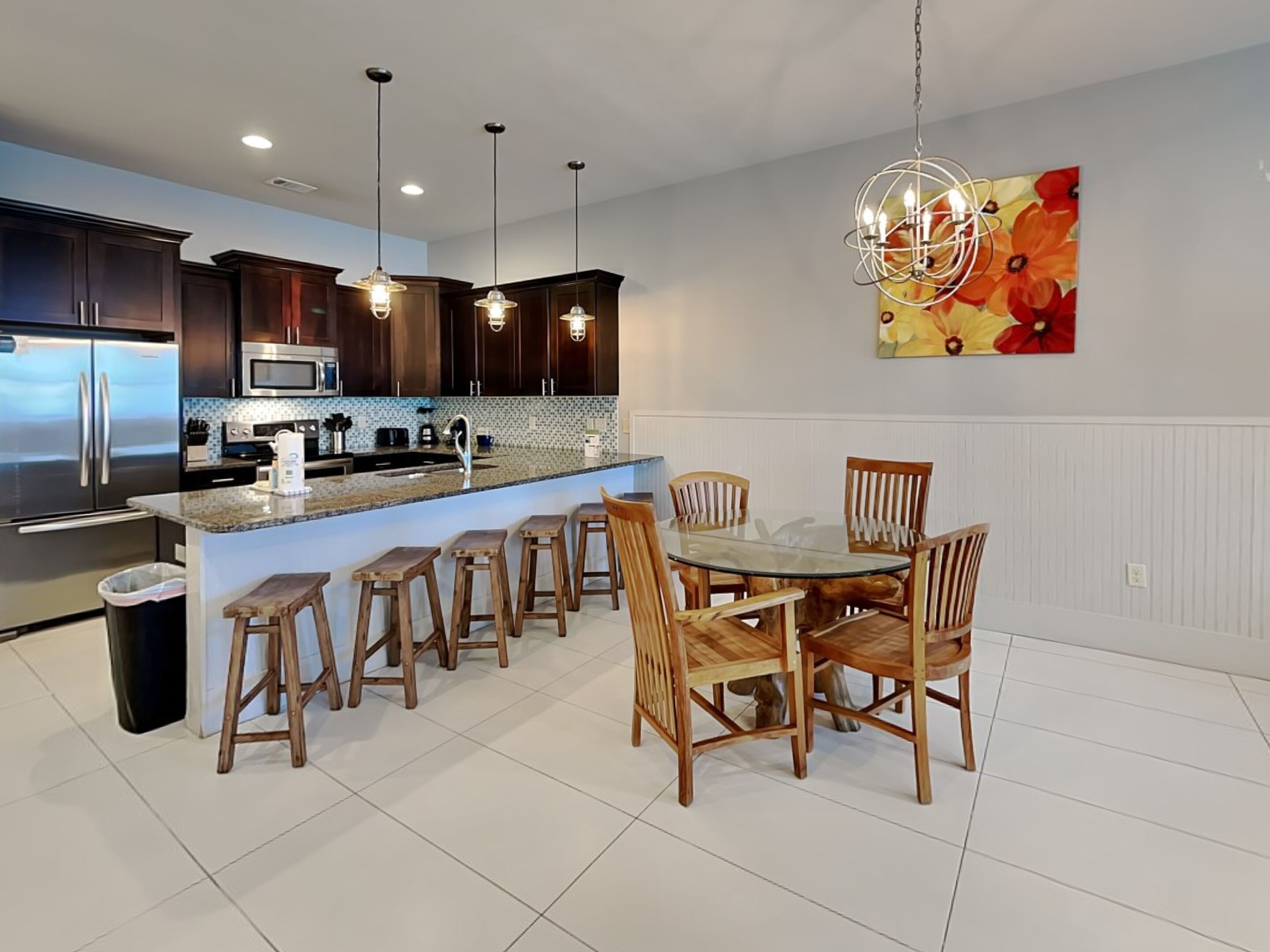 A modern kitchen with dark wood cabinets, stainless steel appliances, and a central island with bar stools.