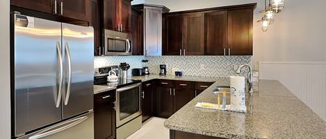 A modern kitchen with dark wooden cabinets, stainless steel appliances, and a granite countertop.