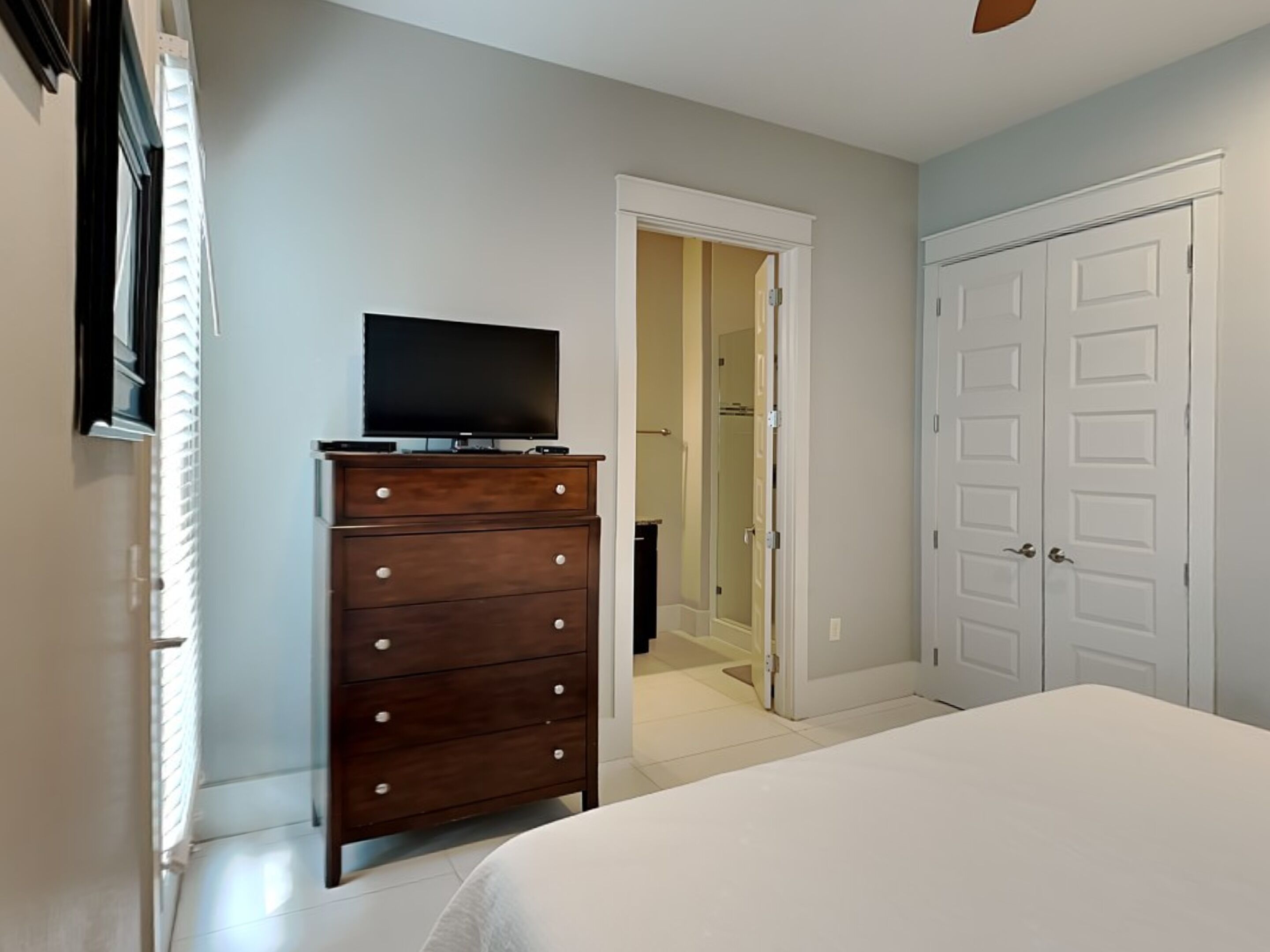 Une chambre à coucher comprenant un lit, une commode, un téléviseur et un placard.