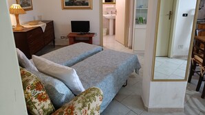 Un dormitorio con cama, escritorio con computadora, cómoda y espejo.