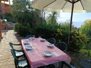 Ein Tisch im Freien mit rot-weißer Karotischdecke, umgeben von Stühlen und einem Sonnenschirm.
