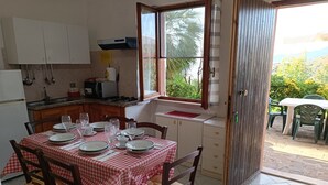 Un comedor con mantel a cuadros, sillas de madera y vistas al exterior a través de una ventana.