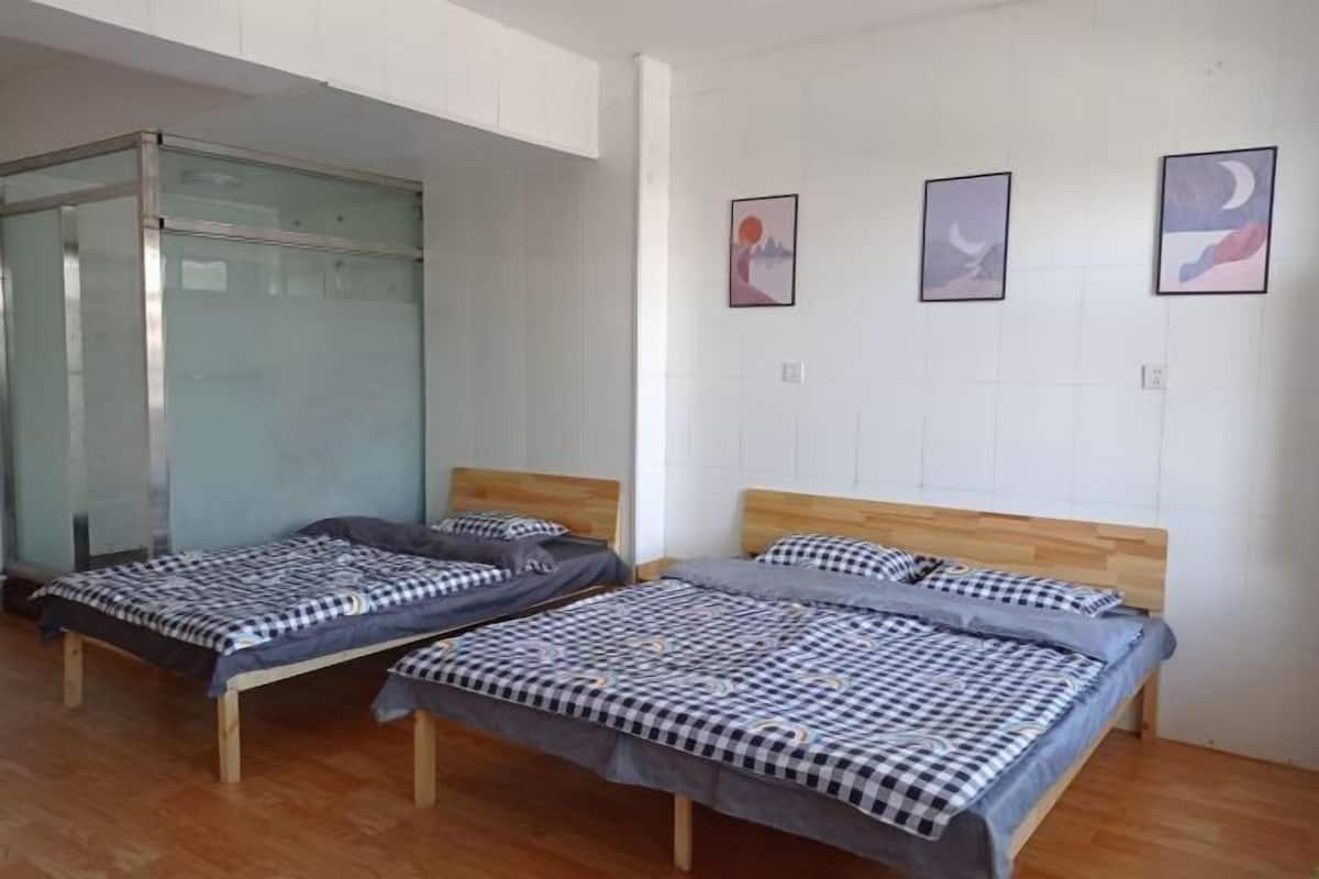 Ein Zimmer mit zwei Betten, einer Glastrennwand und drei gerahmten Bildern an der Wand.