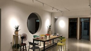 A modern dining area with a long table, chairs, and potted plants.