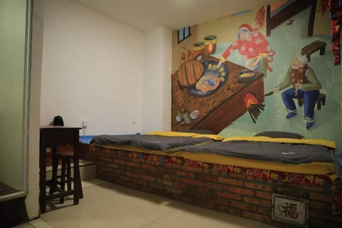 Ein Zimmer mit einem Bett, einem kleinen Tisch und einem Wandgemälde.