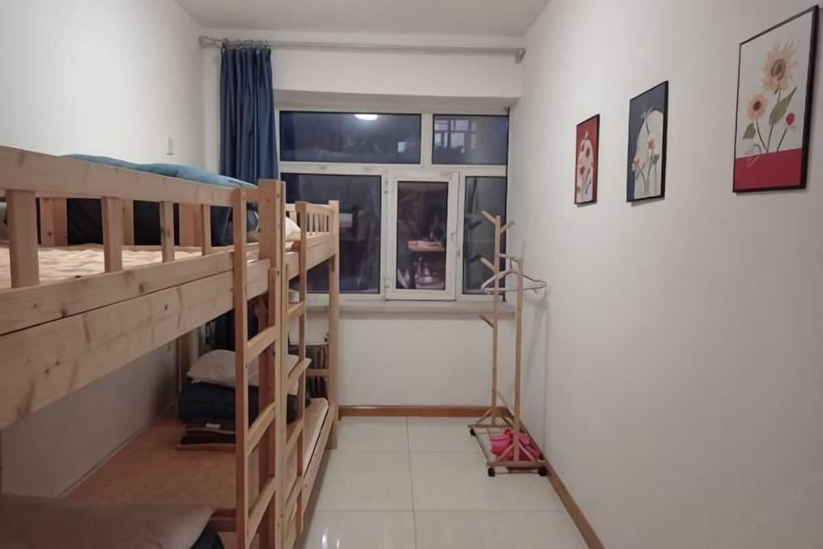 Ein Zimmer mit Etagenbetten, einem Vorhangfenster und Wandbildern.