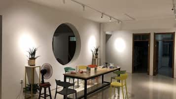 A modern dining area with a long table, chairs, and potted plants.