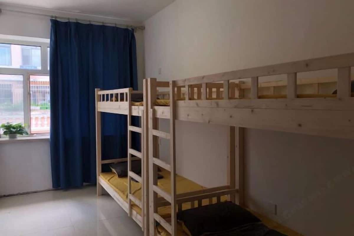 Ein Schlafraum mit Etagenbetten, einem Fenster, Vorhängen und einer kleinen Pflanze.