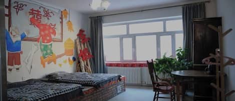A room with a bed, a desk, a chair, a radiator, a window, and a wall with a mural.