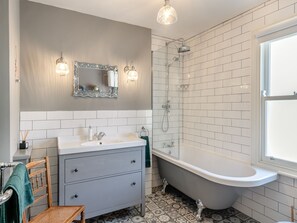 A bathroom with a bathtub, a sink, a mirror, and a shower.