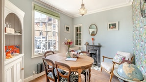 A dining room with a round table, chairs, a fireplace, and a large window.