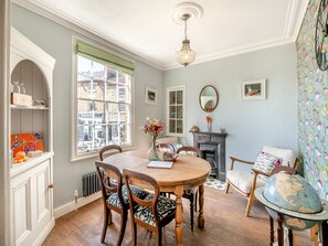 A dining room with a round table, chairs, a fireplace, and a large window.