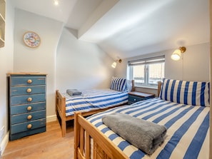 A bedroom with two beds, a dresser, a clock, and a window with a view.