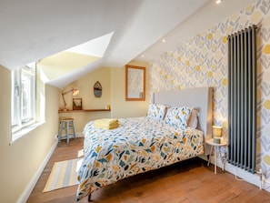Een slaapkamer met een bed, een bureau, een stoel, een radiator en een raam.