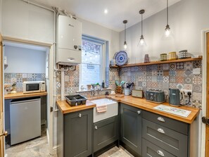 Een moderne keuken met een magnetron, spoelbak en kasten, met een patroon van tegels en hanglampen.