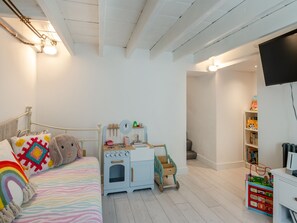 Ein Kinderzimmer mit Bett, Spielküche und Fernseher.