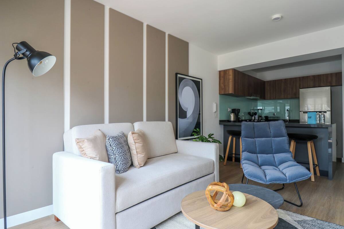 A modern living room with a sofa, a coffee table, a floor lamp, and a blue chair.