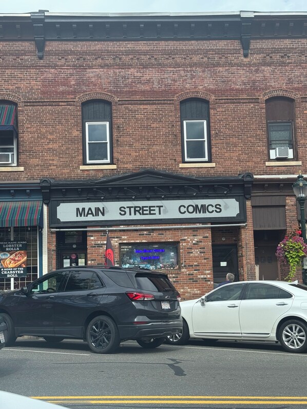 A brick building with a storefront labeled "MAIN STREET COMICS". - Gateway to the Berkshires - Renovated downtown apartment (Lee)