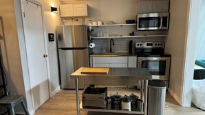 A compact kitchen with a stainless steel refrigerator, microwave, oven, and sink.