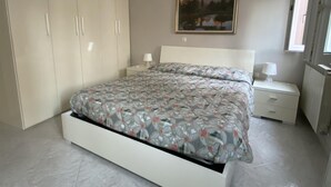 A bedroom with a bed, a nightstand, a wardrobe, and a painting on the wall. - Fairmont Residence Alice by Ca-sa Check (Chioggia)